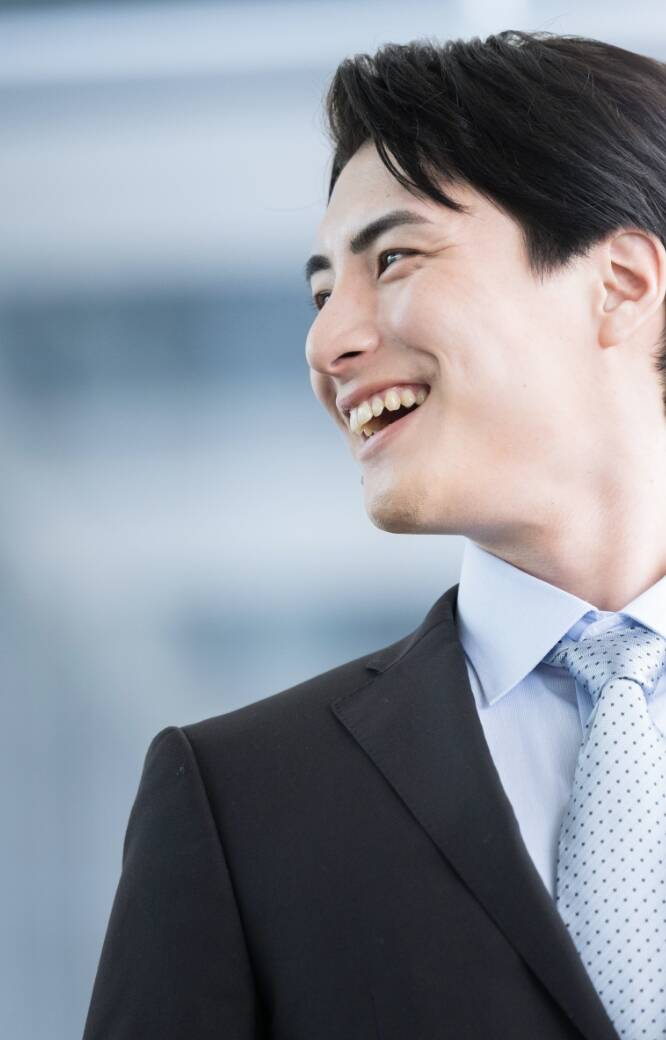 スーツを着用した男性の横顔。黒色のスーツに白系のネクタイを着用している